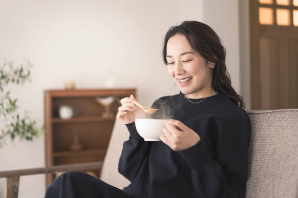 A woman is drinking hot soup.