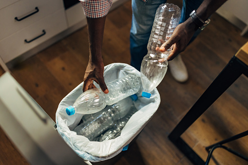 Close-up of the hands of an unrecognizable man throwing plastic waste into a trash can