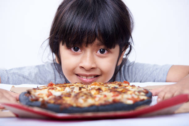 śliczna dziewczynka trzyma czarną pizzę na białym tle - convenience food box humor zdjęcia i obrazy z banku zdjęć