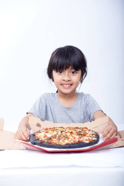 śliczna dziewczynka trzyma czarną pizzę na białym tle - convenience food box humor zdjęcia i obrazy z banku zdjęć