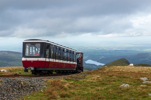 Llanberis, United Kingdom – September 30, 2023: A train traveling along a railway track atop a hill