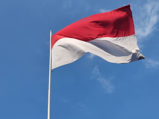 istock Red and white Indonesian flag on clear blue sky background 1718306829