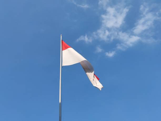 istock Red and white Indonesian flag on clear blue sky background 1718306841