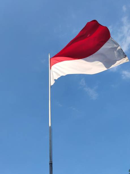 istock Red and white Indonesian flag on clear blue sky background 1718306889