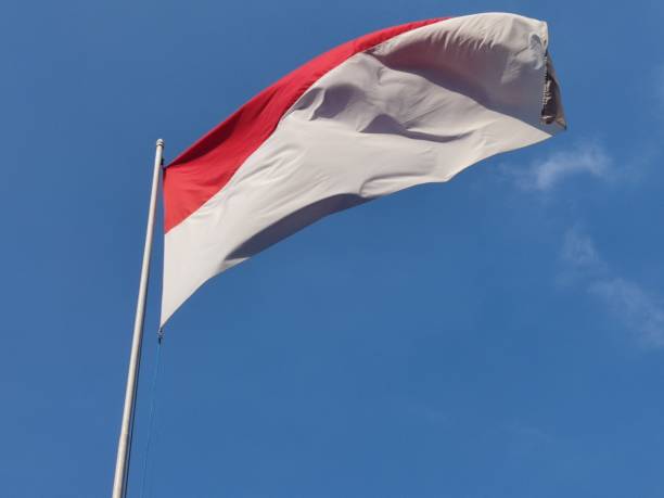 istock Red and white Indonesian flag on clear blue sky background 1718307408
