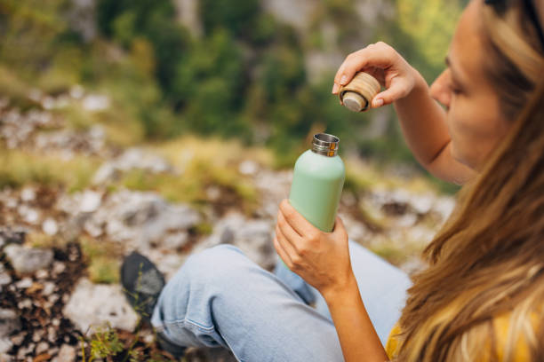 istock A woman opens a reusable bottle after climbing a mountain 1718313512