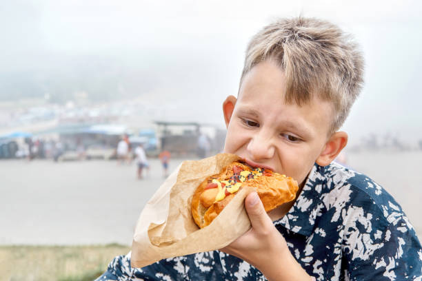 istock Thoughtful boy eats fresh hotdog resting in mountain park 1718324950