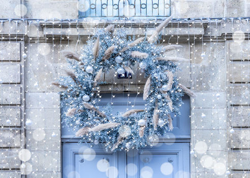 Blue and white rustic Christmas crown and lights on a front door in France