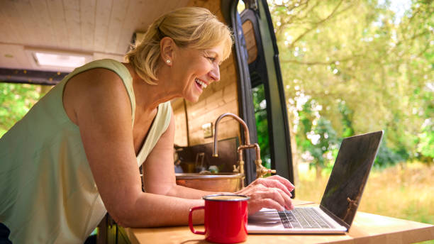 istock Senior Woman On Camping Trip In Countryside Working Inside RV Using Laptop 1718356408