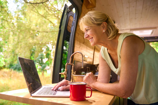 istock Senior Woman On Camping Trip In Countryside Working Inside RV Using Laptop 1718366788