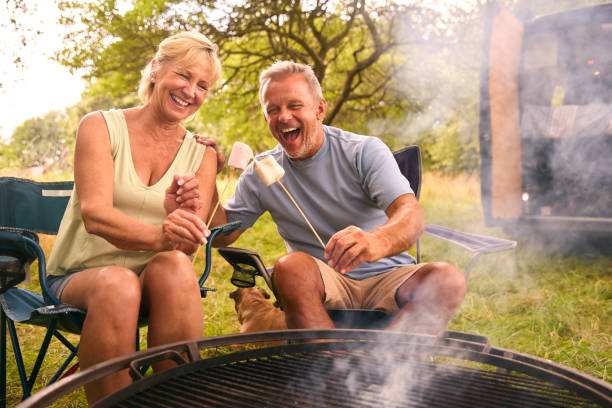 istock Senior Couple Camping In Countryside With RV Toasting Marshmallows Outdoors On Fire 1718368272
