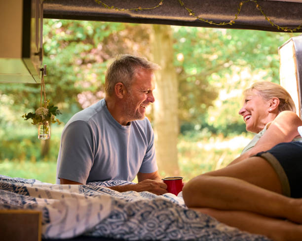 istock Senior Couple Camping In Countryside Relaxing Drinking Coffee Inside RV 1718371095