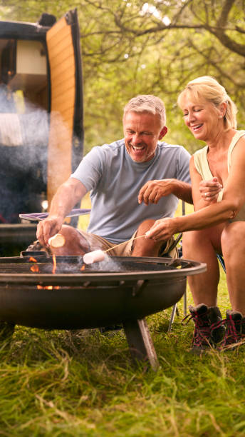 istock Senior Couple Camping In Countryside With RV Toasting Marshmallows Outdoors On Fire 1718372331
