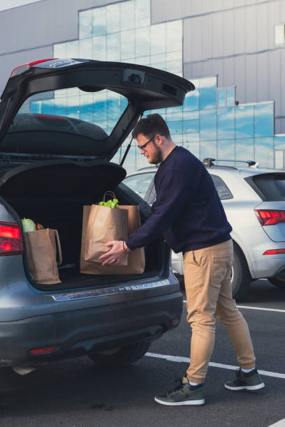 istock happy man put groceries bag in car trunk 1718425713