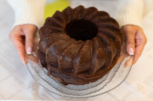 A high angle overhead horizontal photograph of a freshly baked cocoa bundt cake, the baking mold and a serving spatula.