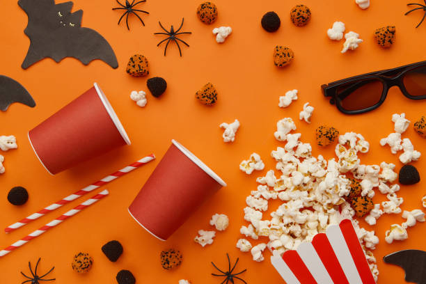 istock Popcorn, clapperboard, paper cup and halloween decor on a red background. Flat lay, copy space. 1718471771