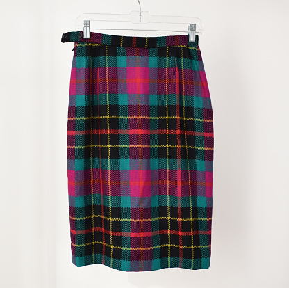 A vibrant wool plaid pencil midi skirt, reminiscent of 80s and 90s vintage winter fashion trends, set against a clean white background.