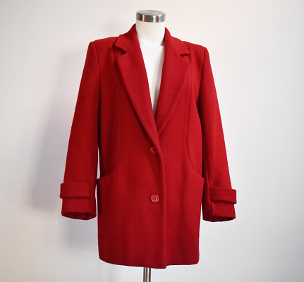 A stylish red wool coat featuring plastic buttons for a trendy and functional cold-weather look.