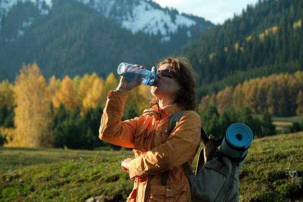 istock Female hiker is taking a break for drink while walking in mountain forest in autumn 1718476830