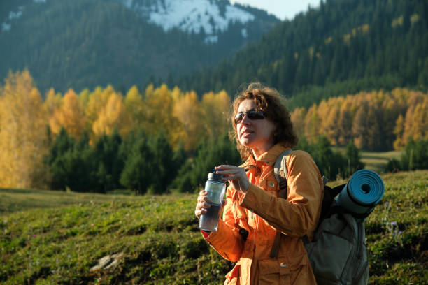 istock Female hiker is taking a break for drink while walking in mountain forest in autumn 1718476884