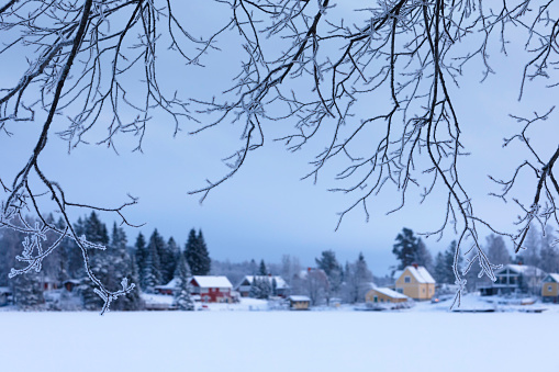 A small village on the shore of a lake in winter with ice and snow in Dalarna, Sweden.