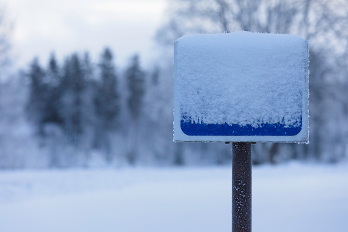 A sign covered in snow on a cold winter day.