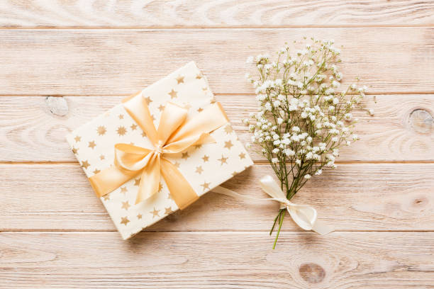 istock Gift or present box and flower gypsophila on light table top view. Greeting card. Flat lay style with copy space 1718485755