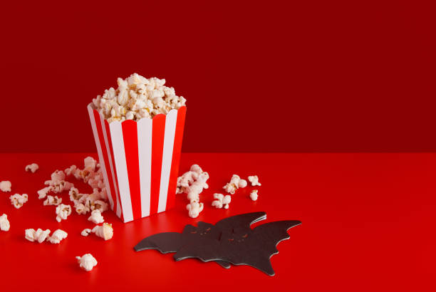 istock Striped box with popcorn, bat napkin on a red background 1718493270