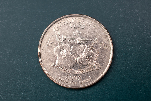 Close up of fingers wearing cotton glove holding US currency,  Indian Head penny from 1862.