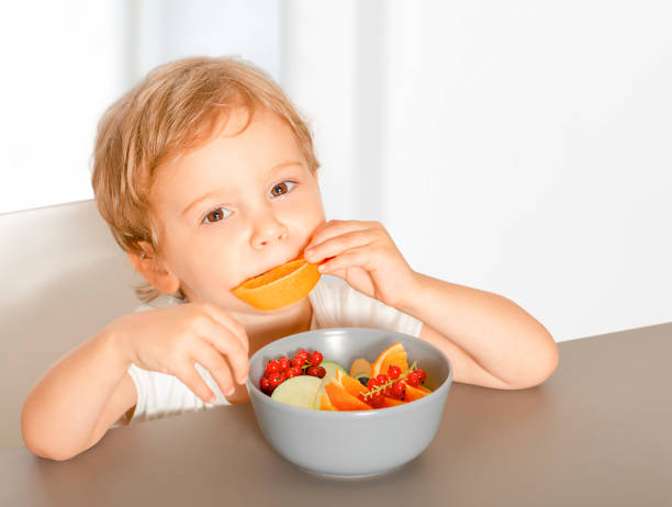 istock Beautiful little baby eats fruits 1718498948