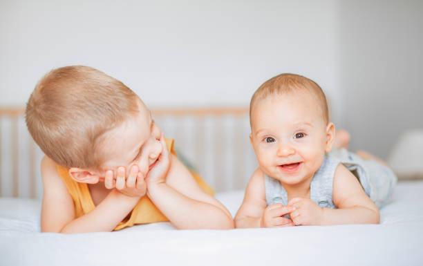 dos bebés sonrientes acostados en la cama - 2 5 meses fotografías e imágenes de stock