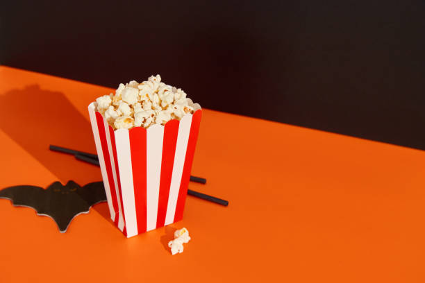 istock Striped box with popcorn, bat napkin and straws on an orange black background 1718501768