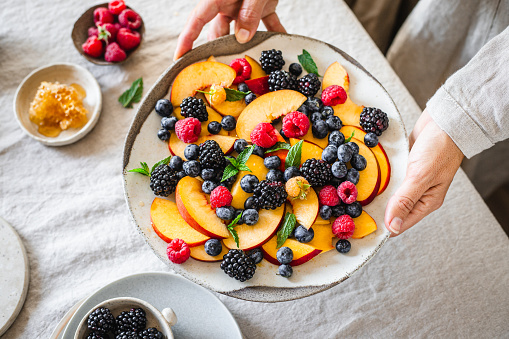 bowl of fresh ripe peaches on a wooden background