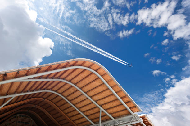 Airliner with contrails flying above a modern airport against a beautiful cumulus clouds or cumulonimbus. Photography, Full frame.