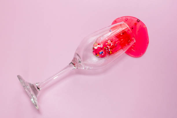 istock Glass with spilled liquid on pink background 1718524240