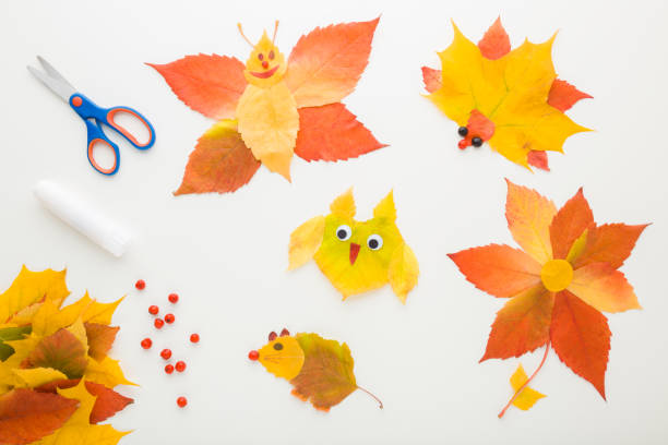 istock Different animal shapes created from colorful leaves on white table background. Making autumn decorations. Closeup. Top down view. 1718529252