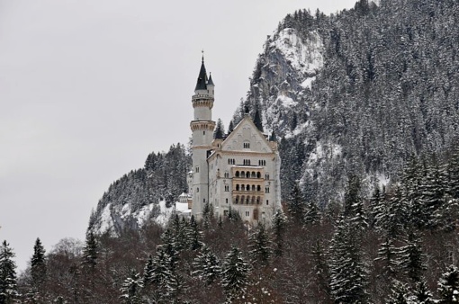 Mountain with trees in winter and in the background View of Neuschwanstein Castle. Hohenschwangau, Bavaria, Germany.