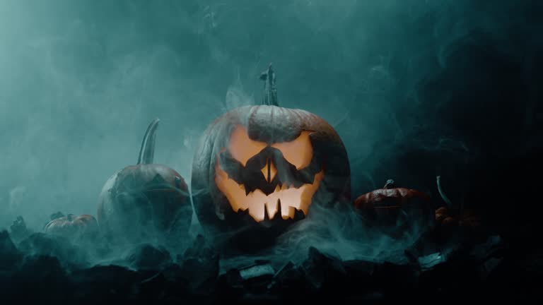 Halloween pumpkin on fire glowing inside in the dark. Scary Pumpkin with smoke around it. Pumpkin glows on Halloween night. Close-up in 4K, UHD