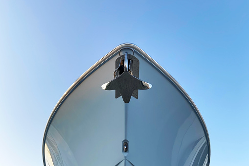 A close-up view of a gleaming metal anchor secured to the bow of a luxurious yacht, set against a backdrop of the sea, showcasing a symbol of maritime elegance and adventure.
