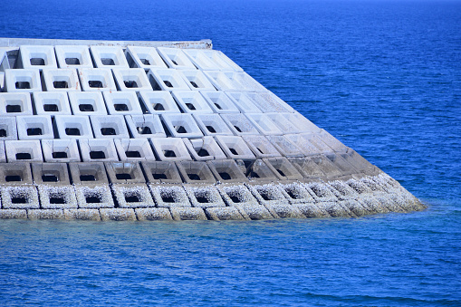 Muscat, Oman: barrier of wave-dissipating hollow cube concrete blocks used to prevent erosion caused by weather and longshore drift, ever more necessary due to rising sea levels induced by climate change. Coastal management.