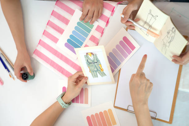 kobiecy zespół projektantów mody omawia projekt odzieży dla klienta z szkicem mody i próbką koloru - owner embroidery small business indoors zdjęcia i obrazy z banku zdjęć