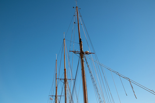 A majestic sailing ship's mast stands tall and proud against the backdrop of a brilliant blue sky, evoking a sense of freedom and adventure.