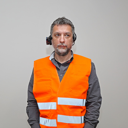 Bearded Senior Worker With Voice Control Headset and Orange Safety Vest