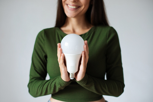 Girl holding a LED light bulb. Using economical and environmentally friendly light bulb concept. Energy saving lamp in woman's hand. Creative business ideas