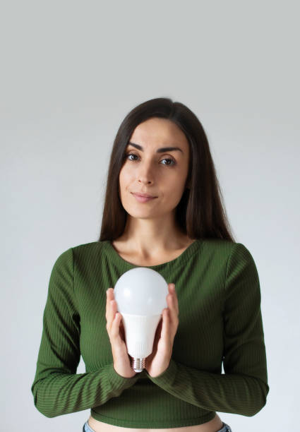 istock Girl holding a LED light bulb. Using economical and environmentally friendly light bulb concept. Energy saving lamp in woman's hand. Creative business ideas 1718660643