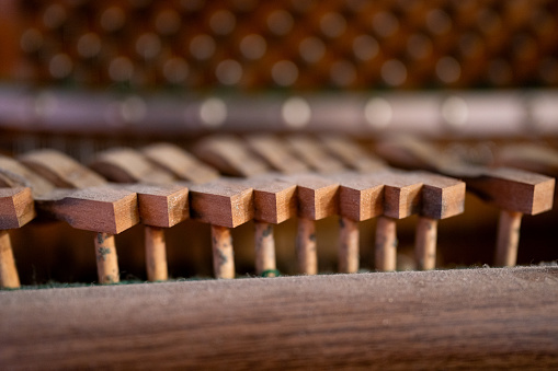 Close-up of old broken dusty piano from the inside. Hammers in abandoned piano striking strings. Music playing from the ancient ruined piano. Gavel of the string open mechanism