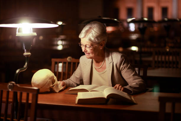 istock Senior woman reading in library at night 1718662318