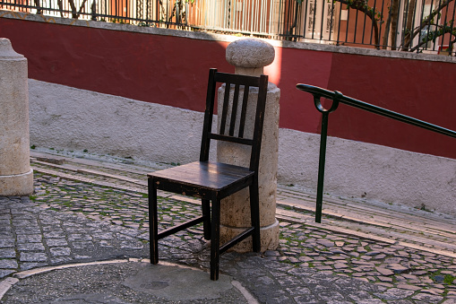 An empty wooden chair sits on a charming cobbled street in the heart of an old European city, inviting passersby to pause and soak in the timeless atmosphere.