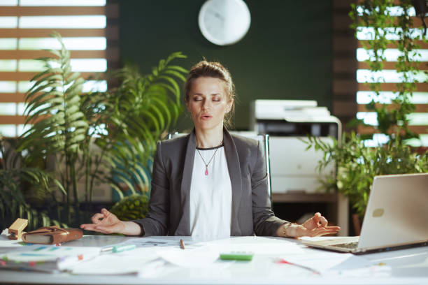 entspannte geschäftsinhaberin im grünen büro meditiert - zen like meditating yoga business stock-fotos und bilder