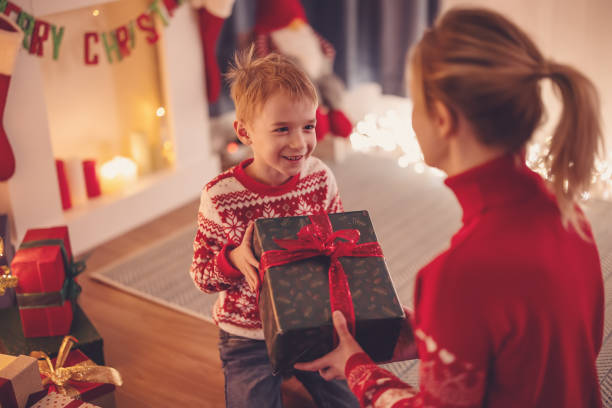 istock Mother giving Christmas gift box to her cute son. 1718686775